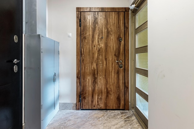 Porte d'entrée en bois de couleur naturelle dans un immeuble à plusieurs étages Entrée de l'appartement