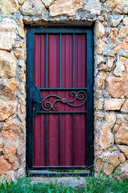 Une porte en métal violet avec une poignée de porte noire dans une paroi rocheuse calcaire.