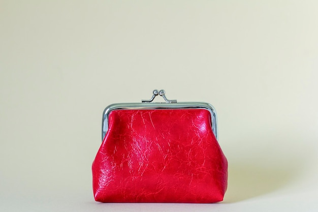 Un porte-monnaie rouge fermé sur fond beige clair avec un endroit pour copier