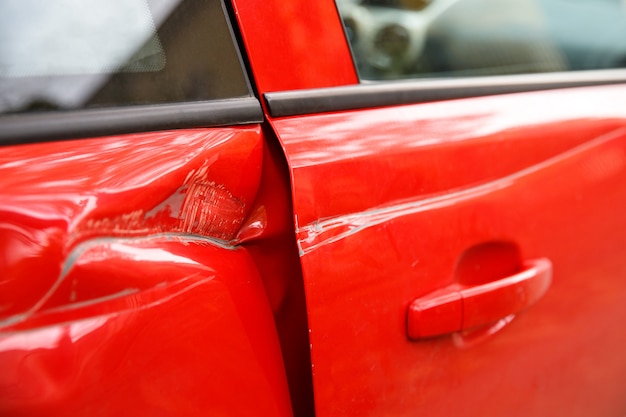 Photo porte rouge voiture endommagée dans un accident de dent profonde, rayures sur les portes