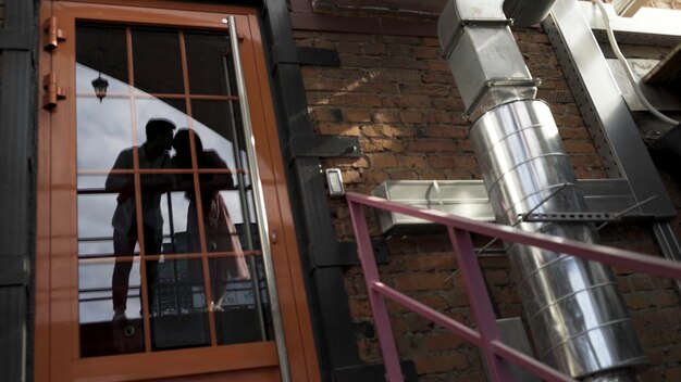 Photo porte en verre avec le reflet d'un homme et d'une femme amoureux s'embrassant les lèvres action reflet d'une belle