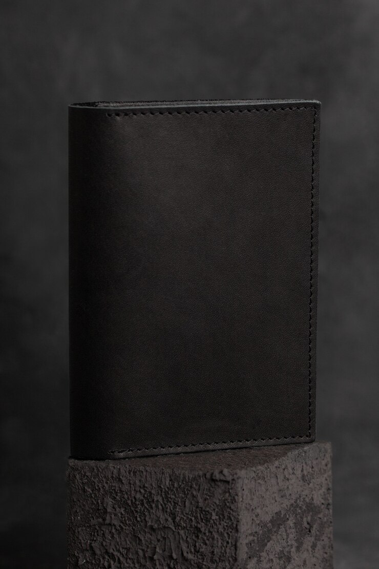 portefeuille en cuir artisanal noir sur une surface en béton