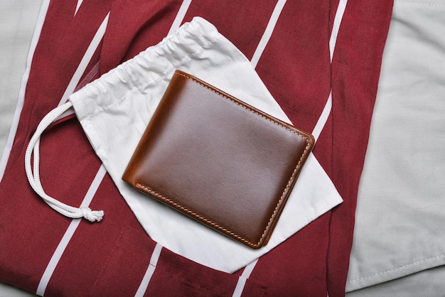 Portefeuille en cuir véritable, portefeuille bifold marron pleine fleur artisanal sur fond de chemise, mode et accessoire pour hommes.