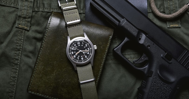 portefeuille et pistolet de montre militaire vintage sur fond vert armée, montre-bracelet mécanique classique, mode et accessoires pour hommes militaires.
