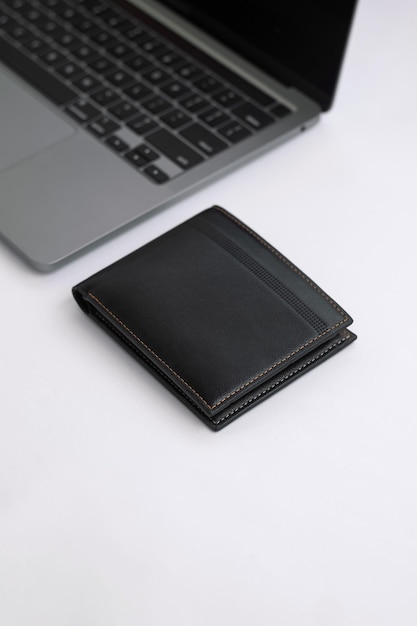 Portefeuille pour homme en cuir noir à la mode avec ordinateur portable sur un bureau blanc table blanche