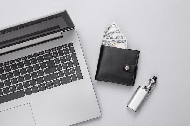Photo portefeuille pour ordinateur portable et appareil de vapotage sur fond gris mise à plat