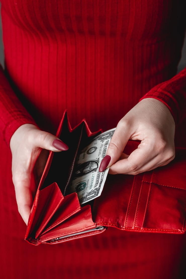 Photo portefeuille rouge entre les mains d'une femme vêtue d'une robe rouge avec manucure rouge