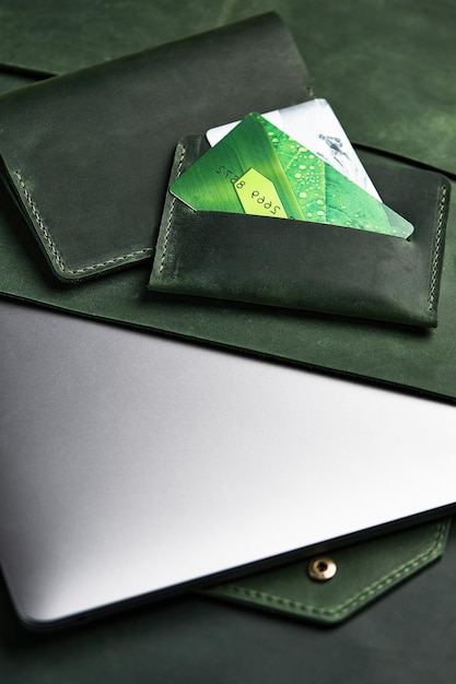 Portefeuille vert et étui pour ordinateur portable en cuir véritable et porte-cartes se trouvent sur la table. Vue de dessus
