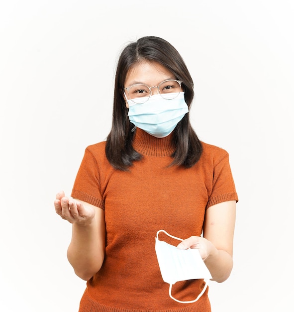 Porter un masque médical pour prévenir le virus Corona et donner un masque de belle femme asiatique isolée sur fond blanc
