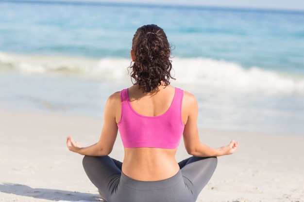 Porter la vue de la femme en forme faire du yoga au bord de la mer