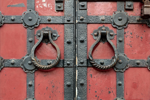 Portes anciennes rouges avec les ferrures métalliques et les poignées de porte rondes.