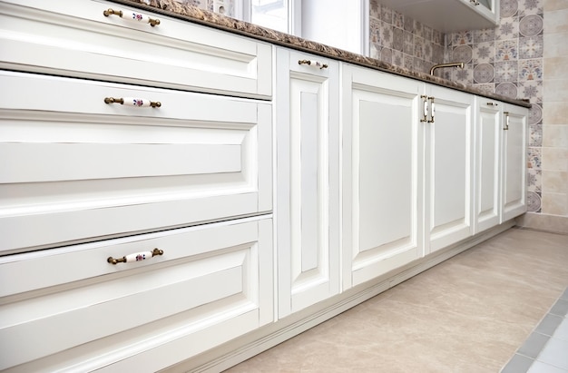 Portes et tiroirs de cuisine de cuisine blanche dans un style campagnard avec gros plan de comptoir en granit