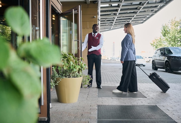 Photo portier de l'hôtel rencontrant le client et lui ouvrant la porte