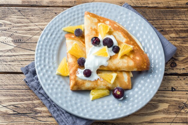 Une portion de crêpes avec des baies et de la crème dans l&#39;assiette.