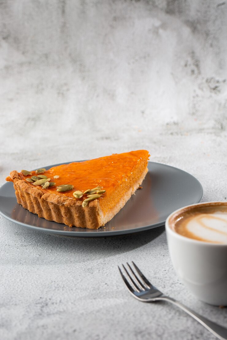 Portion de délicieuse tarte à la citrouille orange vif sur plaque grise, décorée de graines de citrouille avec fourchettes à dessert gros plan, vue de dessus. Fond de marbre clair. Copiez l'espace. Verticale. menu pour café
