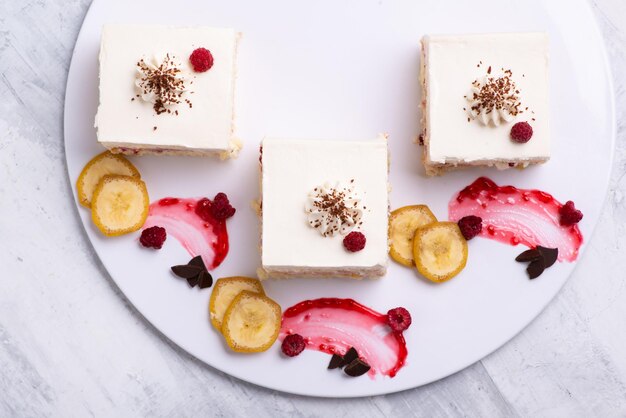 Portion de délicieux morceaux de gâteau à la vanille aux fruits sur une assiette blanche