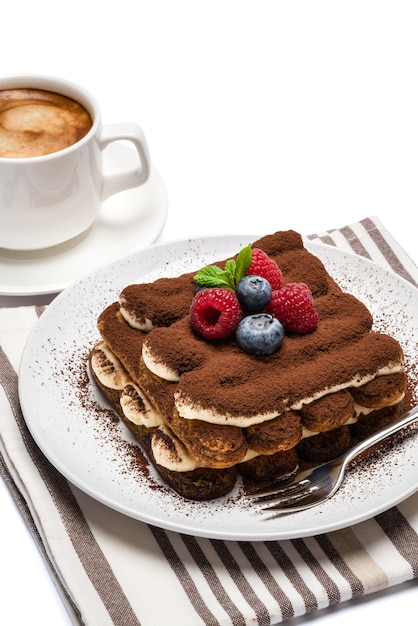 Portion de dessert tiramisu classique avec des baies sur une assiette en céramique