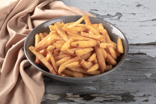 Portion de frites dans un bol sur table rustique.