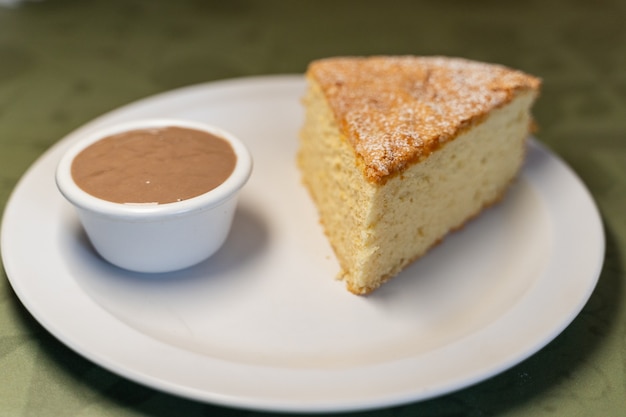 Portion de gâteau santiago servie avec sauce au chocolat dans un plat en céramique blanche dans un restaurant