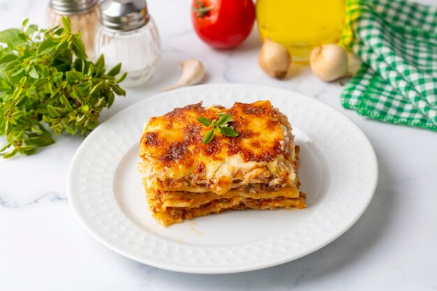 Portion de lasagne de boeuf haché garnie de fromage fondu et garnie de persil frais servi sur une assiette en vue rapprochée pour un menu