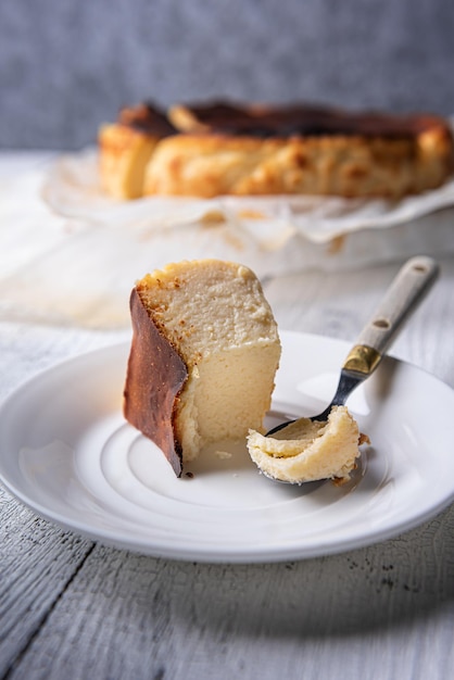 Portion mordue de gâteau au fromage brûlé basque sur une assiette blanche avec une cuillère vintage sur le côté