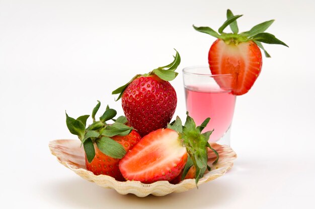 Portion originale de fraises dans une coquille et une boisson aux baies sur fond blanc