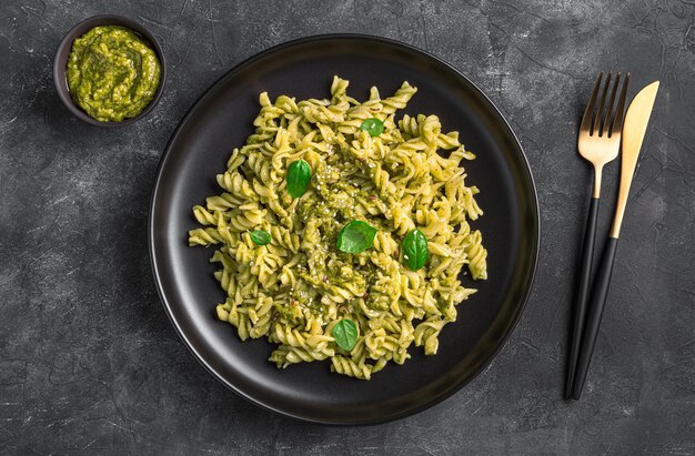 Une portion de pâtes au pesto de basilic sur fond sombre Vue de dessus horizontale