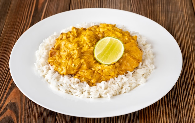 Portion de poulet au curry garni de riz et citron vert frais