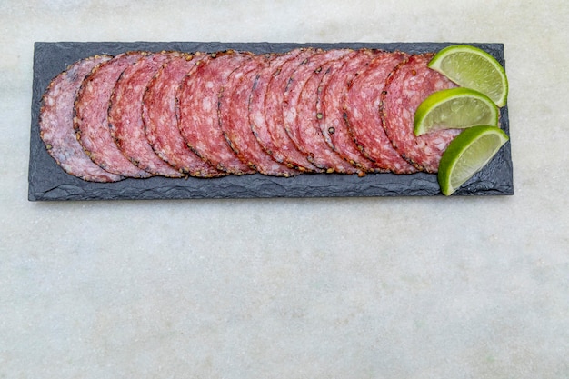 Portion de salami sur plaque de pierre noire