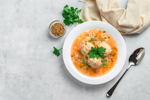 Une portion de soupe avec boulettes de viande, riz et légumes sur fond gris clair. Vue de dessus, copiez l'espace.