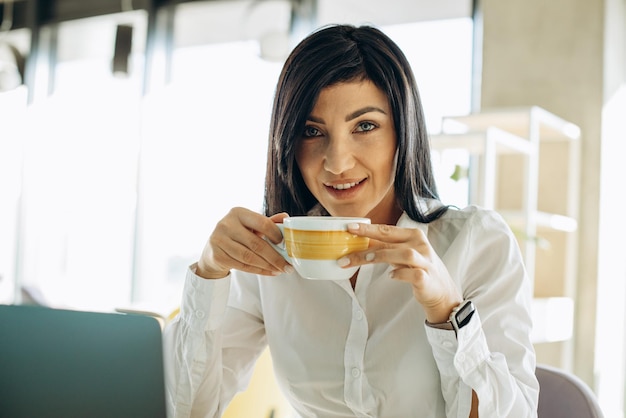 Portrai de jeune femme d'affaires buvant du café au travail