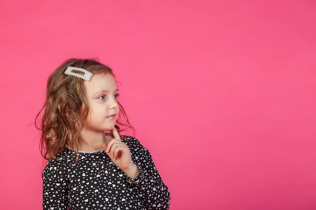 Portrait 5-6 ans fille en robe sur fond isolé rose ressemble à la caméra