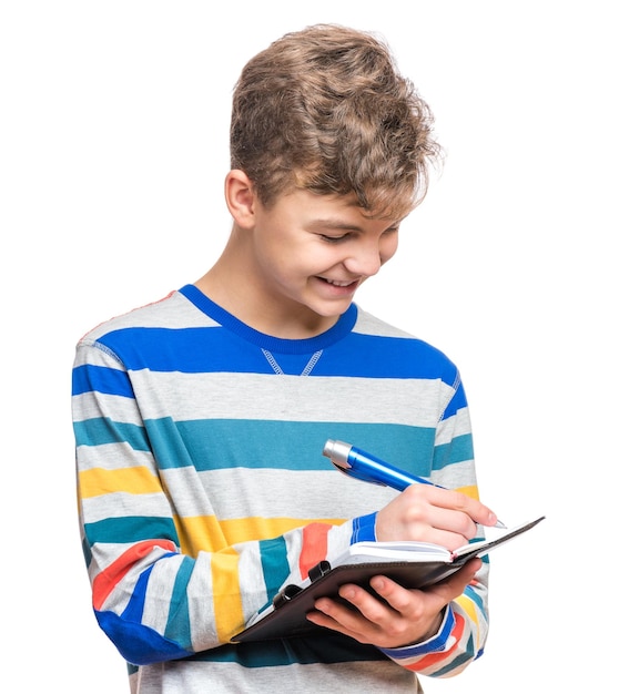 Photo portrait d'un adolescent caucasien souriant avec un cahier et un stylo bleu écrivant quelque chose un adolescent drôle et beau isolé sur un fond blanc un étudiant heureux écrivant sur un bloc-notes