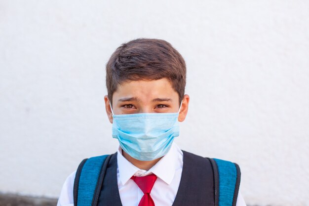 Photo portrait d'un adolescent d'écolier triste dans un masque médical