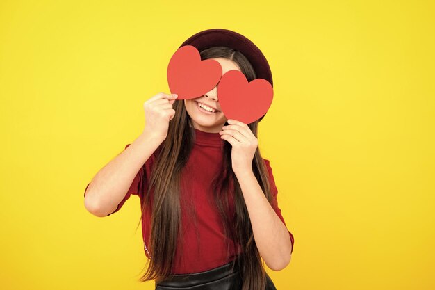 Portrait d'adolescent heureux Enthousiaste belle adolescente romantique tenir coeur rouge symbole de l'amour pour la Saint Valentin isolé sur fond jaune