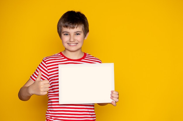 Portrait d'un adolescent heureux avec un morceau de papier sur fond jaune