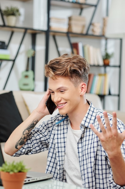 Portrait d'un adolescent souriant beau parler au téléphone avec un ami et discuter des devoirs