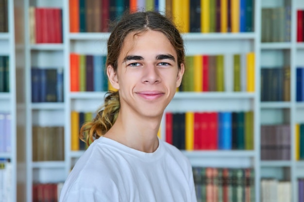 Portrait d'un adolescent souriant regardant la caméra dans la bibliothèque