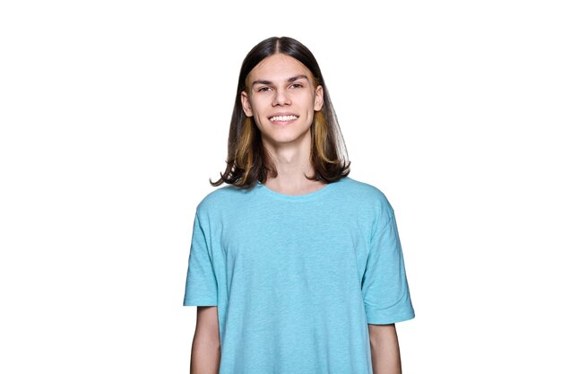 Portrait d'un adolescent souriant regardant la caméra sur fond blanc isolé Beau jeune homme avec une coiffure de cheveux longs posant en studio