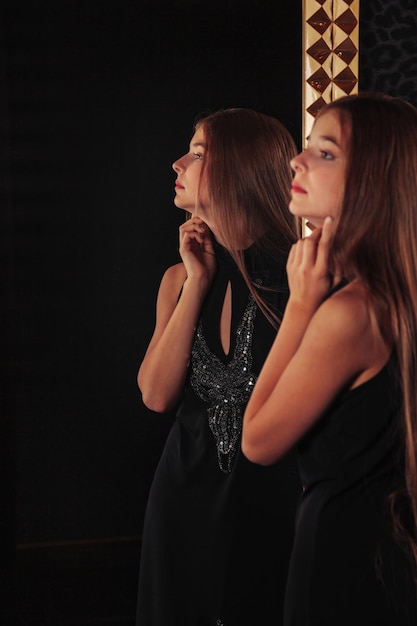 Portrait d'une adolescente assez mignonne vêtue d'une robe élégante au miroir