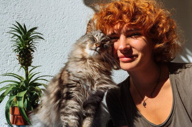 Portrait d'une adolescente aux cheveux roux et d'un chat moelleux au soleil