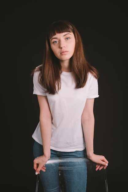 Portrait d'une adolescente debout sur un fond noir