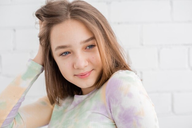 Portrait d'une adolescente élancée dans un col roulé léger à la lumière naturelle contre un mur de briques blanches. beauté naturelle, pas de maquillage. peau problématique. espace pour le texte. Photo de haute qualité