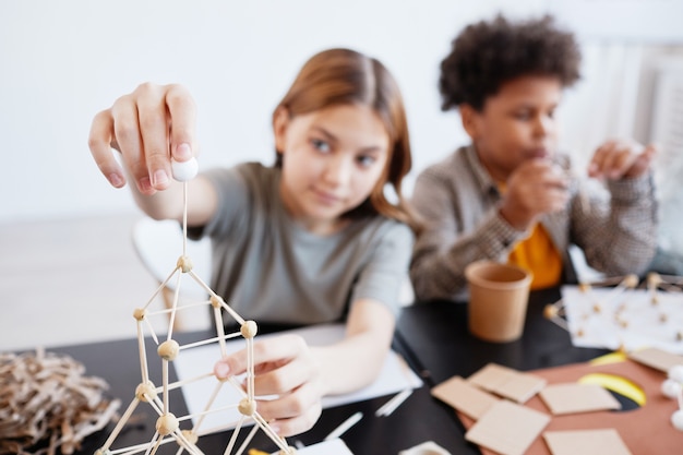 Photo portrait d'une adolescente faisant des modèles en bois pendant les cours d'art et d'artisanat à l'école, mise au point sur le premier plan