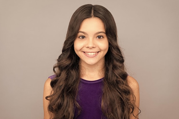 Portrait d'une adolescente heureuse avec un coiffeur aux longs cheveux bouclés