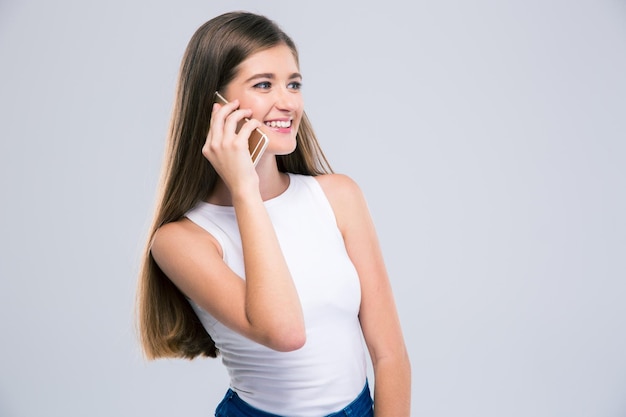 Portrait d'une adolescente heureuse parlant au téléphone isolé