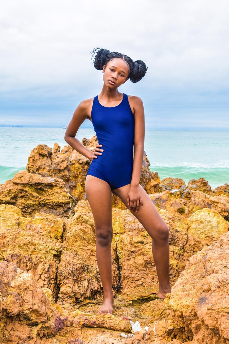 Photo portrait d'une adolescente en maillot de bain debout sur un rocher à la plage contre le ciel