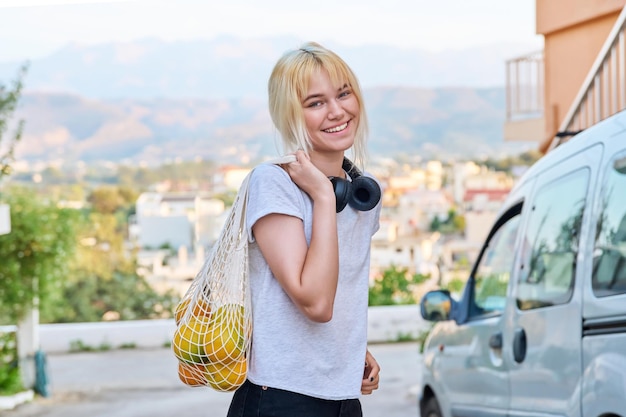 Portrait d'une adolescente avec des oranges dans un sac en filet écologique