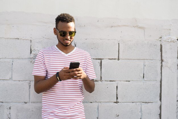 Photo portrait d'une adolescente portant des lunettes de soleil debout contre le mur