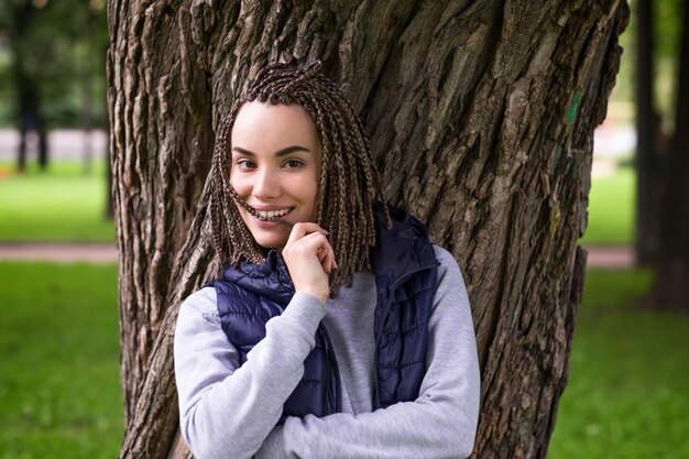 Portrait d'une adolescente positive avec des tresses tressées Elle sourit largement et regarde avec confiance